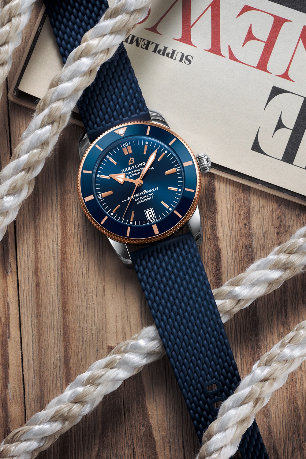 A dark blue Superocean Heritage lies on a table with a magazine and a white rope.