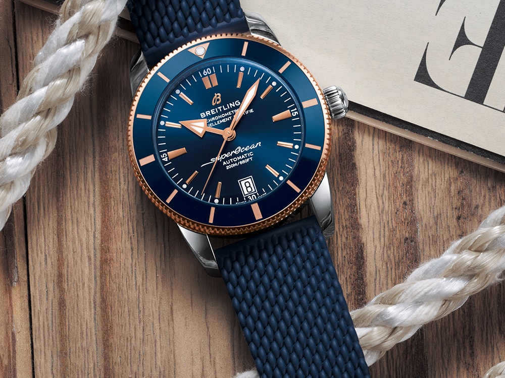 A dark blue Superocean Heritage lies on a table with a magazine and a white rope.