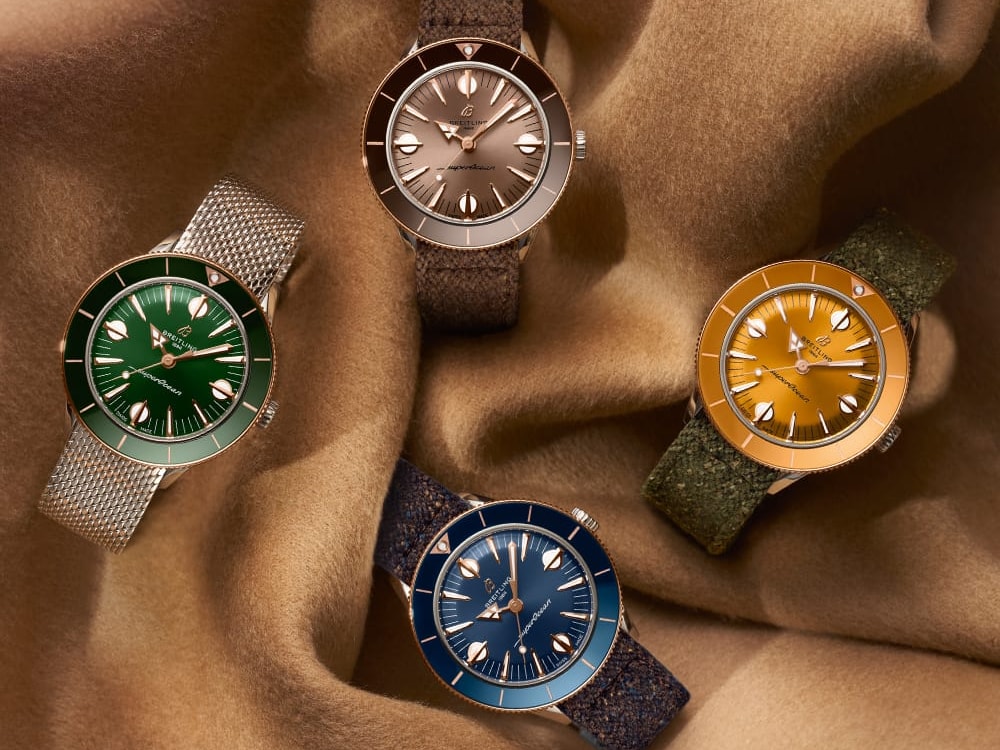 Four different colored Superocean Heritage watches lie on a brown cloth.