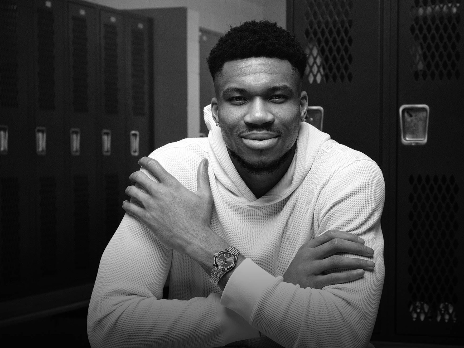 a man standing in front of lockers with his arms crossed