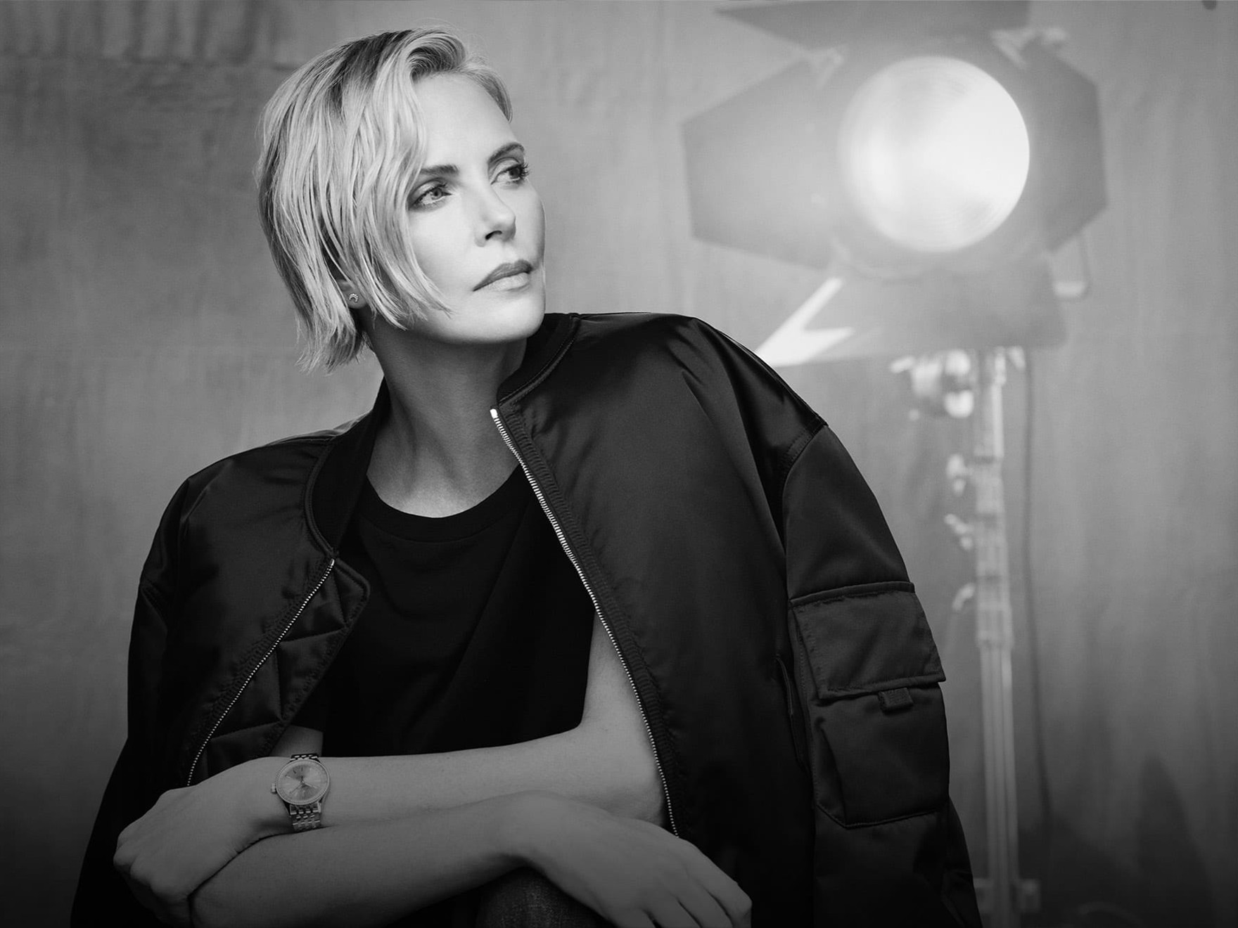 Black and white portrait, woman with short hair, wearing a jacket, spotlight in background.