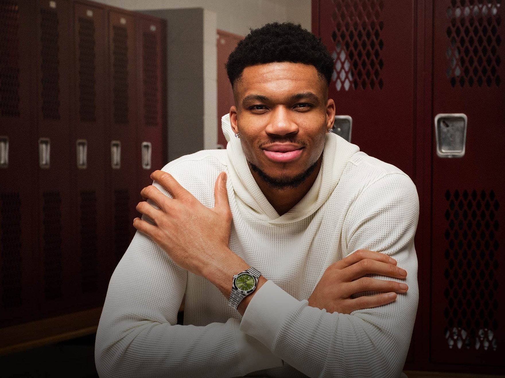 a man standing in front of lockers with his arms crossed