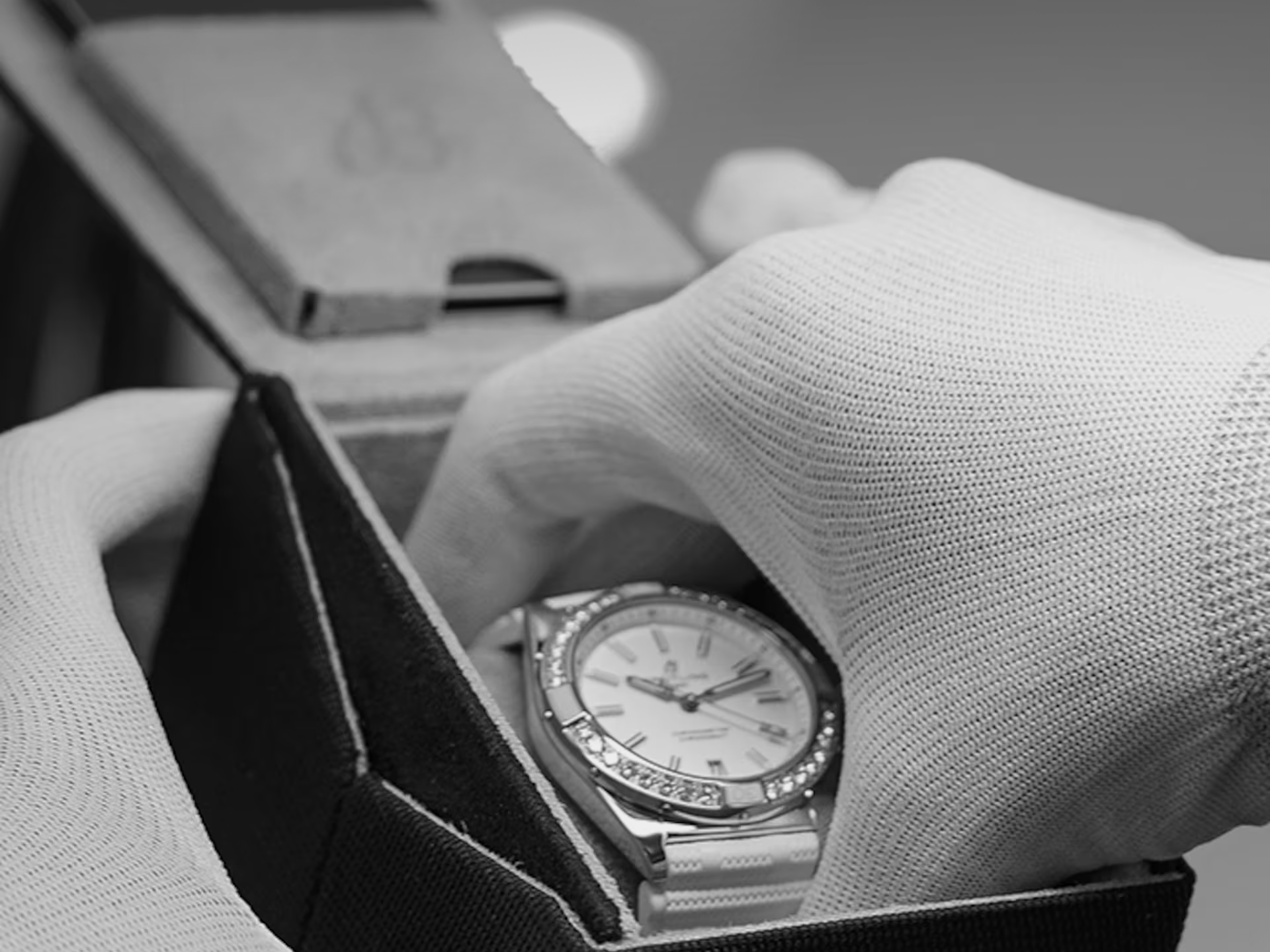 Carefully and with gloves on, a Breitling watch is taken out of its packaging.