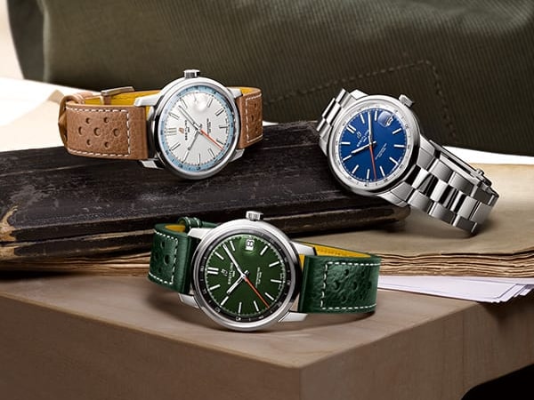 Three Top Time watches with different colored dials and straps on a shiny background.