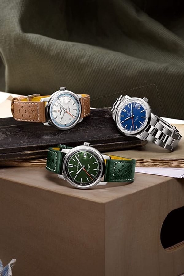 Three Top Time watches with different colored dials and straps on a shiny background.
